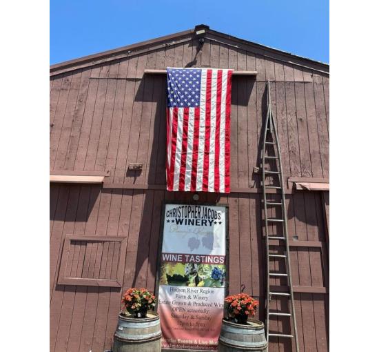 the barn at winery with american flag hanging, logo on the building blue skies and a ladder going up the barn