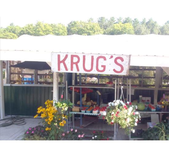 Farm stand with white roof and sign with red font