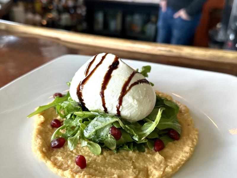 Hummus, burrata, and greens on a plate