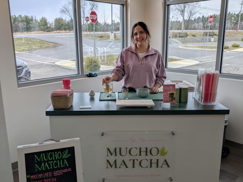 Karina posing at the cart set up for an indoor event, with the menu board in the foreground
