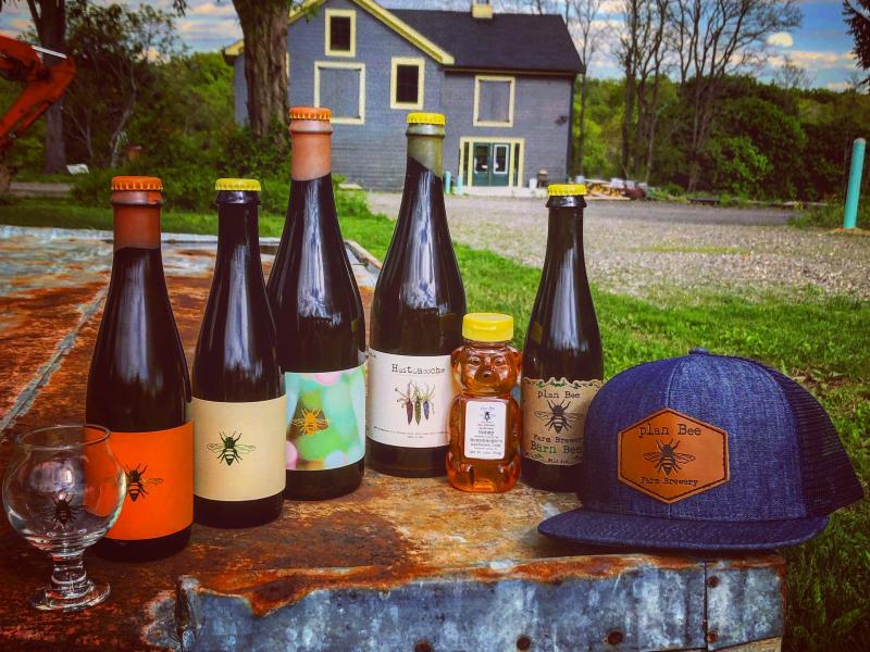 outside on a table sits the bottles plan bee farm brewery sells
