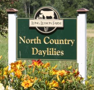 green sign outside of the farm with flowers in front